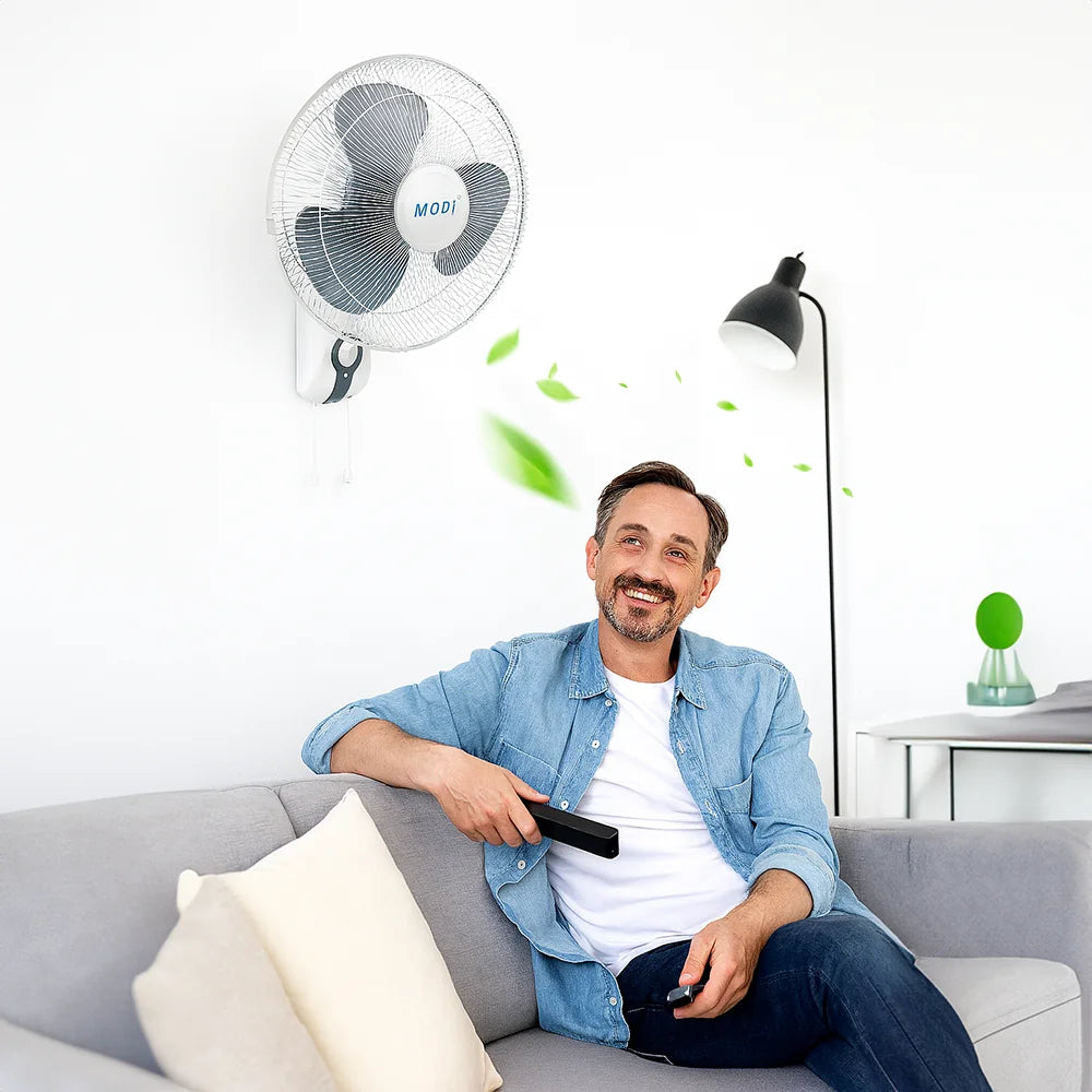 A man sitting on a sofa enjoying the breeze from a 16-inch Wall Fan, demonstrating the ideal cooling solution for home comfort.