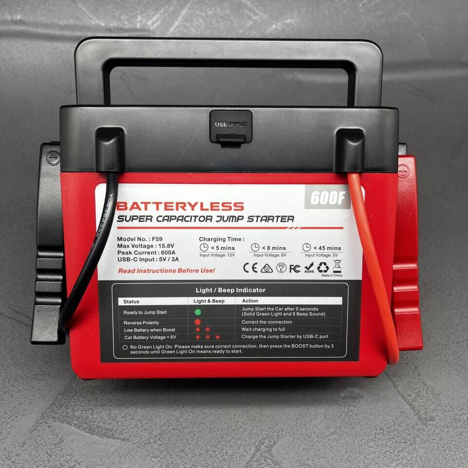 Red and black batteryless super capacitor jump starter on a gray textured background